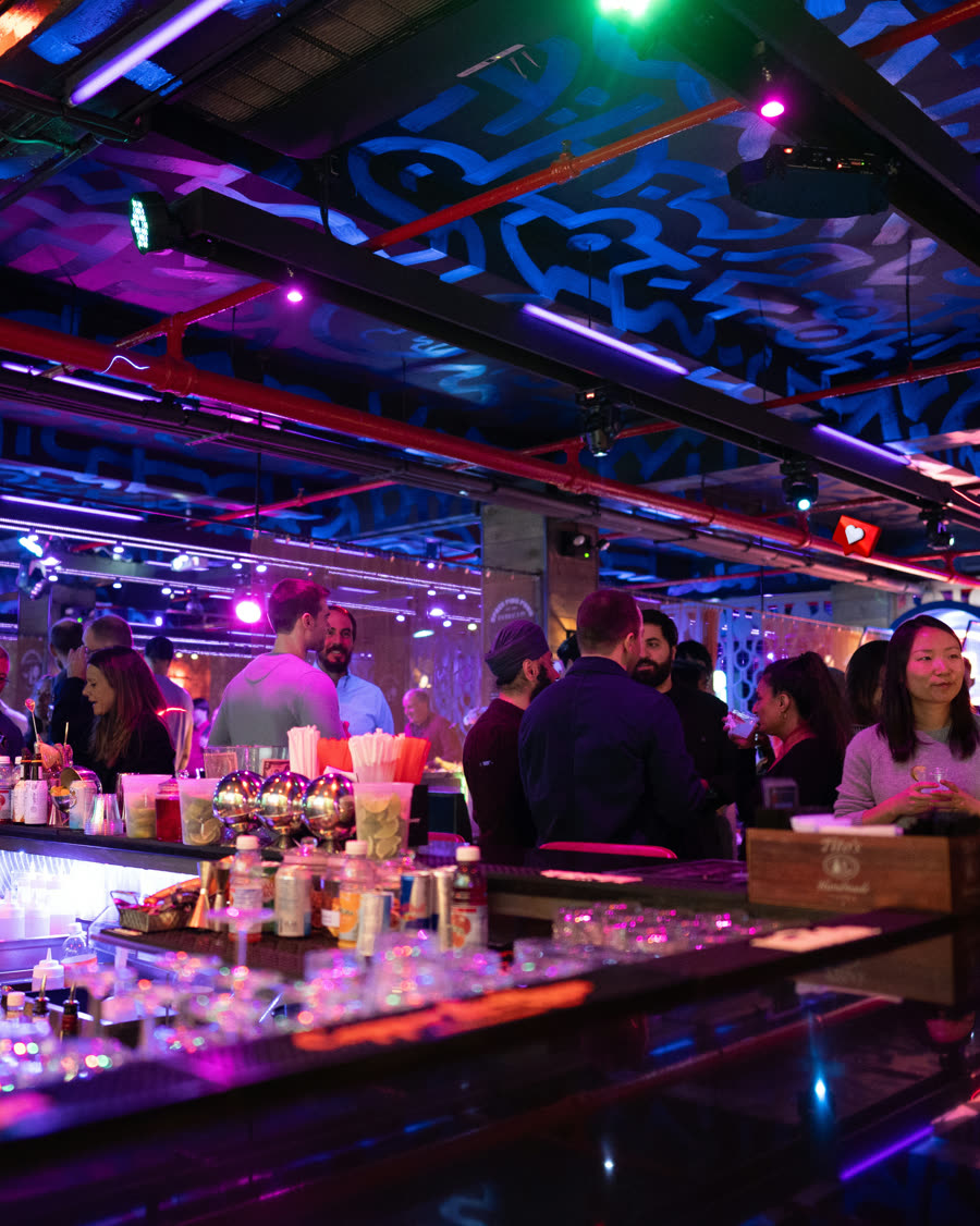 Guests gathered around the Space Ping Pong bar under purple venue lighting